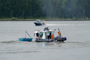 Policjanci w motorówce zabezpieczają łódź na wodzie