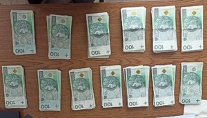 pieniądze o nominale 100 złotych leżą na stole w kilku kupkach
