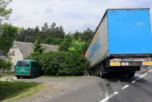 uszkodzony z lewej strony zielony pojazd i pojazd ciężarowy z naczepą uderzyły w płot posesji
