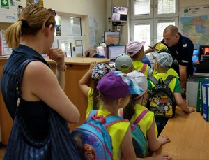 Dzieci oglądają pomieszczenie dyżurnego komisariatu.