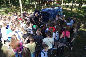 Plaża w Borównie. Bardzo duża grupa dzieci skupiona wokół radiowozu z psami policyjnymi.