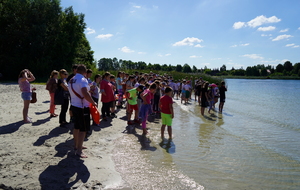 Plaża w Borównie. Dzieci pod nadzorem policjanta stoją na brzegu jeziora.