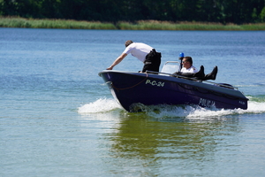 Jezioro w Borównie. Policjanci płyną łodzią motorową. W łodzi leży wyciągnięty z wody mężczyzna.