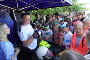 Dzieci przy stoisku policjantów Wydziału Prewencji. Policjant prezentuje alkogogle.