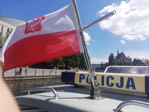 Ujęcie flagi powiewającej na policyjnej łodzi motorowej.