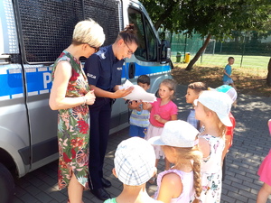 policjantka oraz pracownik cywilny Policji rozmawiają z dziećmi przed policyjnym radiowozem