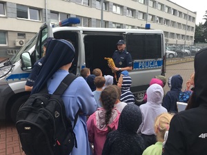 policjant pokazuje dzieciom wyposażenie w policyjnym radiowozie