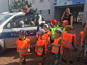 Policjantka prezentuje dzieciom radiowóz policyjny.