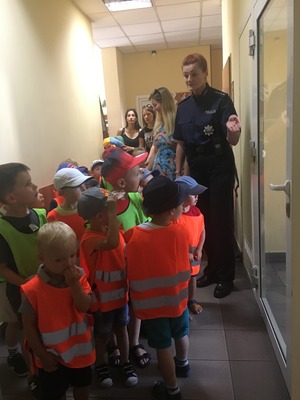 Policjantka pokazuje dzieciom pomieszczenia w komisariacie.
