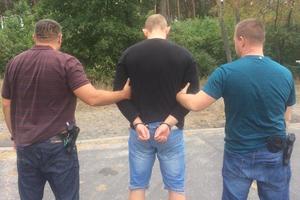 policjanci trzymają zatrzymaną osobę zakutą w kajdanki