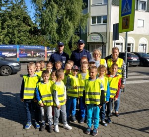 Zdjęcie grupowe dzieci i policjantów przed budynkiem szkoły.