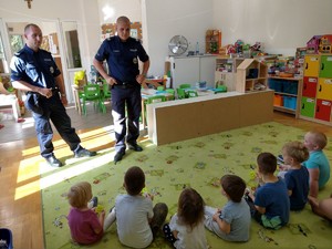 Policjanci rozmawiają z przedszkolakami w sali.