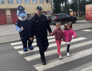 Polfinek, policjanci i dzieci ćwiczą przechodzenie przez przejście dla pieszych.
