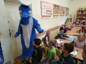 Polfinek wita się z dziećmi w klasie szkolnej.
