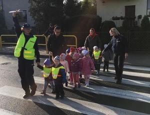 Dzieci z policjantami na przejściu dla pieszych.
