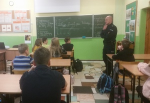 Policjant i uczniowie podczas zajęć w klasie szkolnej.