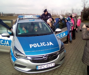 Policjant pokazuje dzieciom radiowóz i jego wyposażenie.