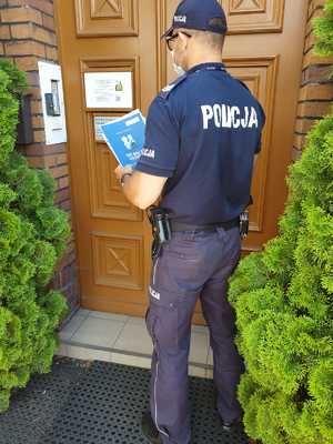 Policjant wręcza dokumenty księdzu
