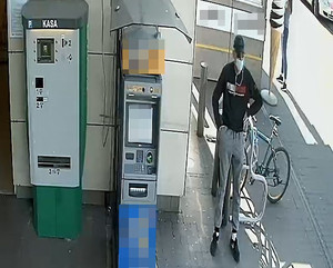 Poszukiwany mężczyzna stojący obok bankomatu.