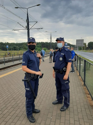 Policjanci wraz z innymi osobami stoją na przystanku tramwajowym.