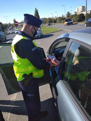 Policjant podaje kierowcy pojazdu deklarację do podpisania.