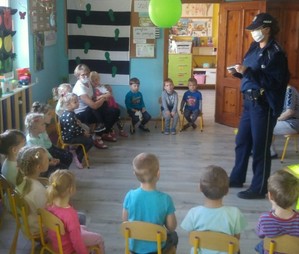 Policjantka prowadzi zajęcia z dziećmi w sali przedszkola.