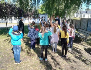 Policjant wraz z dziećmi podczas zajęć na świeżym powietrzu- teren zielony przy szkole (2)