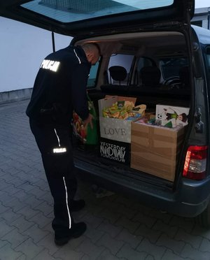 policjant pakuje zebrane dary do bagażnika radiowozu.
