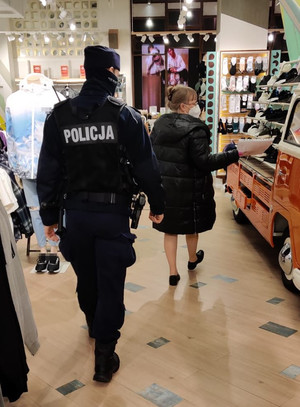 Pracownik Sanepidu wraz z policjantem idą przez teren sklepu.