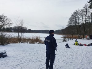 Policjant podczas kontroli terenu przy jeziorze.