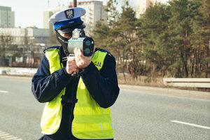 Policjant mierzy prędkość ręcznym miernikiem prędkości