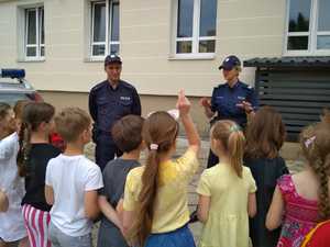 policjanci rozmawiają z dziećmi koło radiowozu