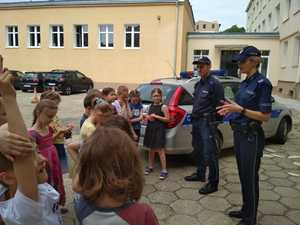 policjanci rozmawiają z dziećmi koło radiowozu