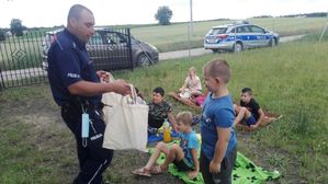 Policjant rozdaje dzieciom upominki.