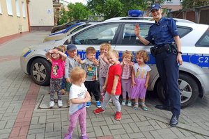 policjantka pozuje do zdjęcia razem z dziećmi przed radiowozem