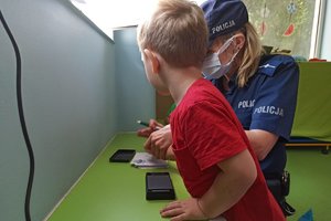 policjantka daktyloskopuje palec chłopca na pamiątkowej karteczce