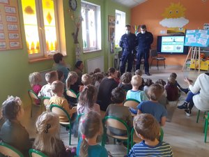 Dzieci i policjanci podczas zajęć w sali przedszkola.