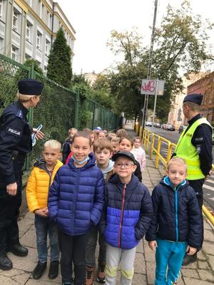 Dzieci wraz z policjantami idą chodnikiem.
