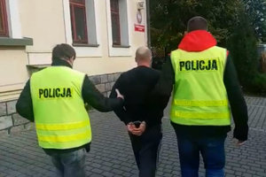 dwaj policjanci prowadzą zatrzymanego skutego kajdankami