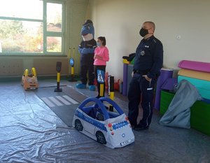 Policjanci oraz Polfinek podczas zajęć z dziećmi na sali gimnastycznej przedszkola.