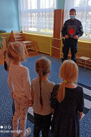 policjant pokazuje trójce dzieci czerwone światło na kartce