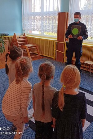 policjant pokazuje trójce dzieci zielone światło na kartce
