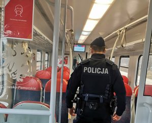 Policjant kontroluje przedział w pociągu.