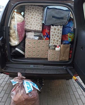 Kartony i worki z darami dla zwierząt spakowane do bagażnika samochodu.