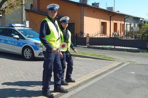 Policjant i policjantka stoją przy radiowozie