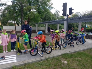 Dzieci na rowerach i hulajnogach pod czujnym okiem policjantów.